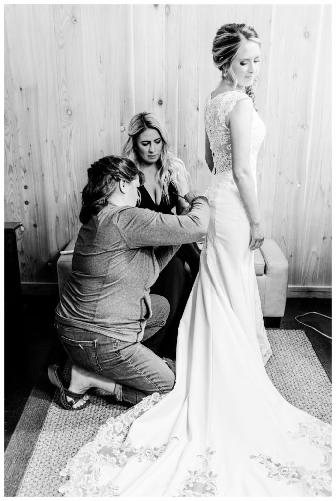 Mother helping daughter get into wedding dress. A summer wedding at Clyde Iron Works in Duluth, Minnesota. Photo by Kayla Lee.