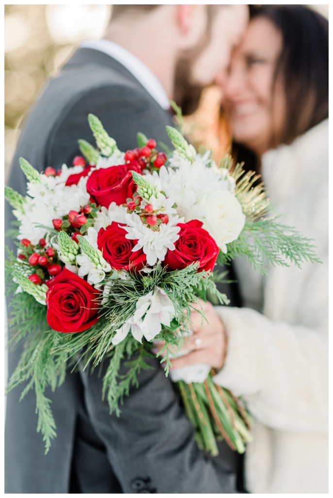 A red and green Christmas-inspired bouquet from a winter elopement at Gunflint Lodge. Photography by Kayla Lee.