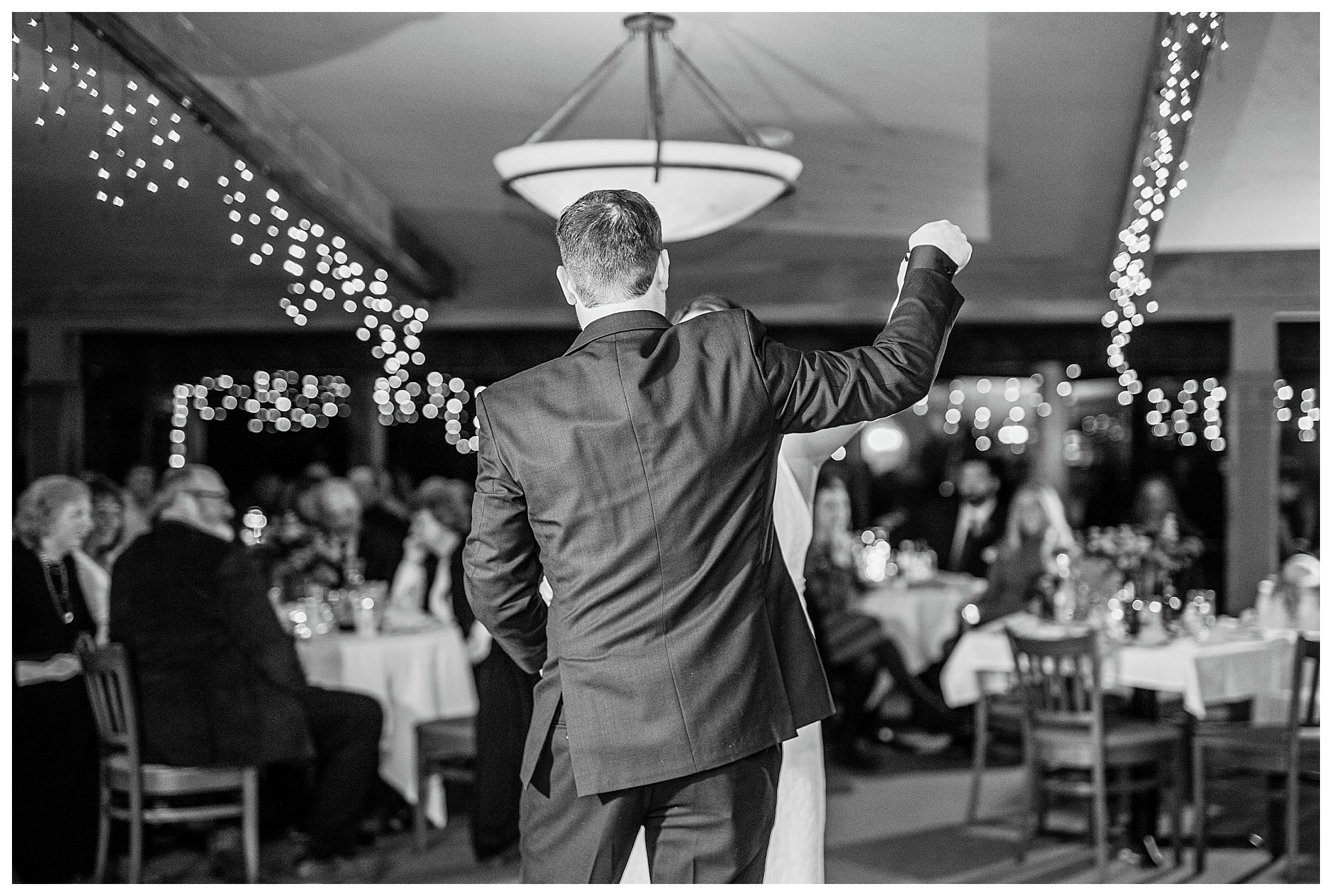 Black and white photo of a groom twirling his bride during their first dance. Photo by Kayla Lee.