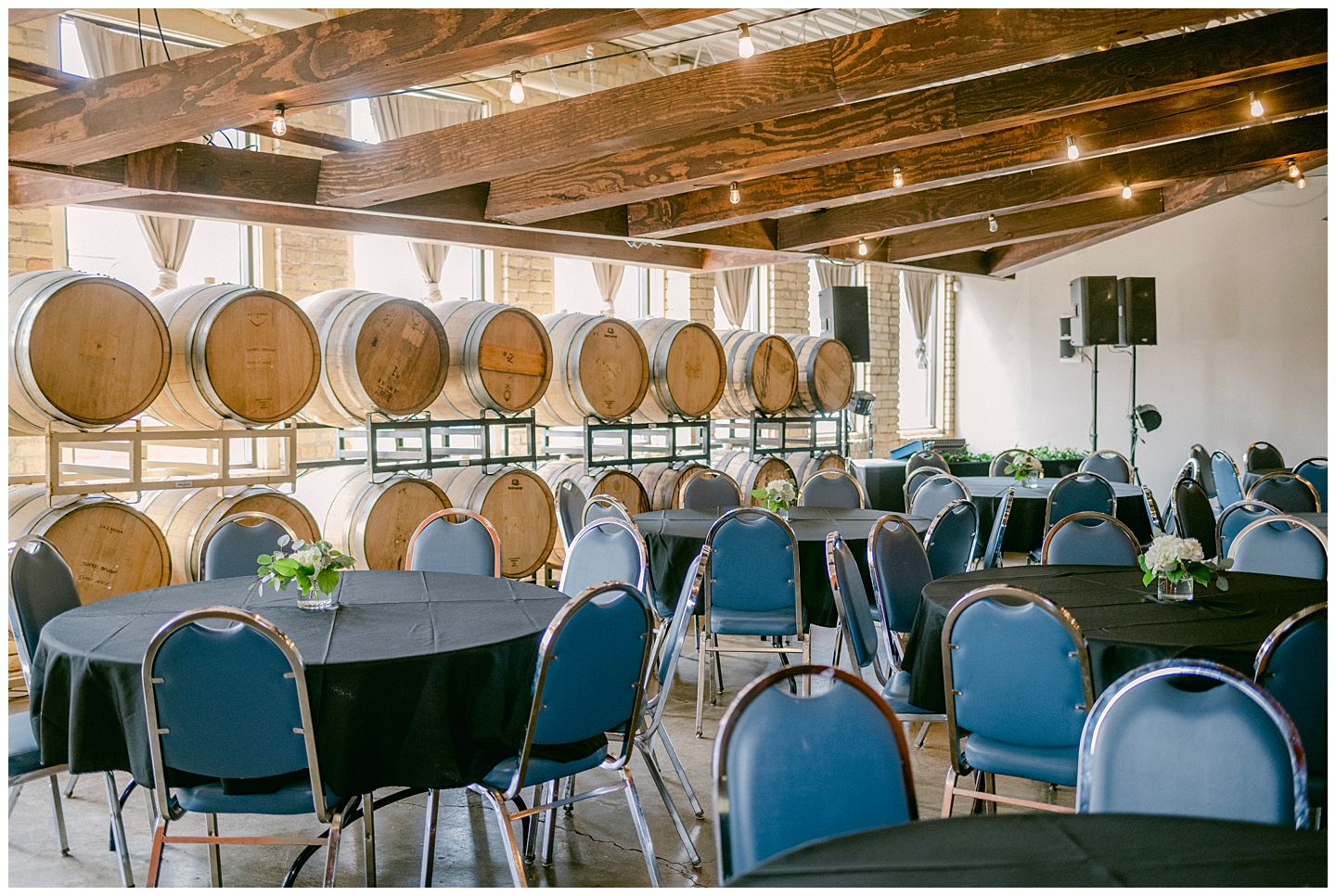 Barrell Room at St. Paul's Urban Growler Brewery set up for a wedding with blue chairs and black tablecloths. Photo by Kayla Lee.