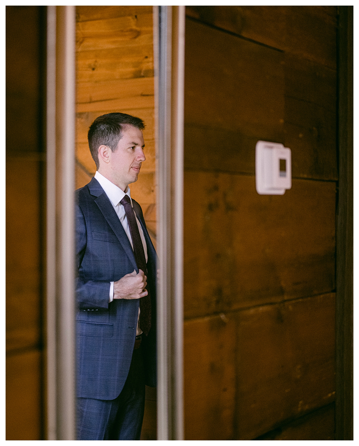 A groom getting ready, looking in the mirror, in the barn at a Mayowood Stone Barn Wedding. Photo by Kayla Lee.